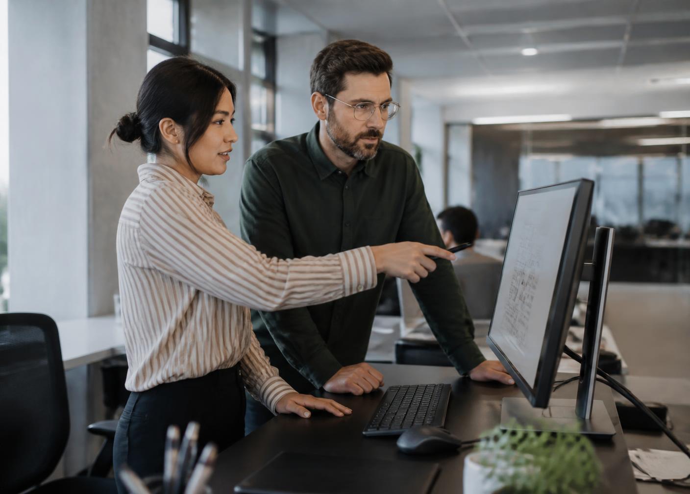 Colleagues reviewing a shared document library on a laptop while working together at a desk